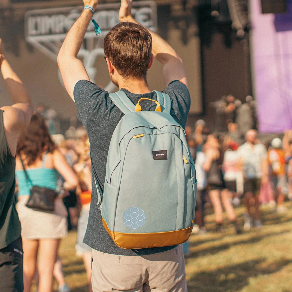 Plecak antykradzieżowy Pacsafe Go na plecach mężczyzny unoszący ręce w góre, pokazanie plecaka z siatką eXomesh