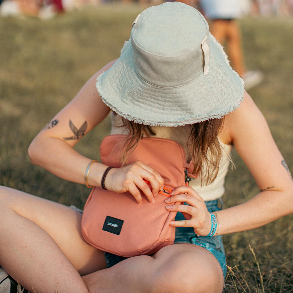 Torebka marki Pacsafe z z serii Go dziewczyna siedząca na trawie